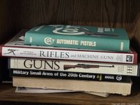Stack of five firearm reference books on shelf