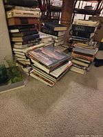 Stacks of hardcover and paperback books on carpeted floor