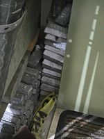 Tall vertical stack of lead ingots behind cabinet