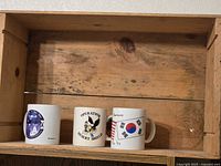Overall view of the three mugs sitting inside wooden crate
