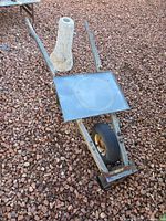 Wheelbarrow frame and stone pedestal on gravel