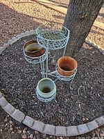 Full view of metal plant stand and four ceramic pots