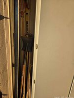 Group of long-handled garden tools in closet