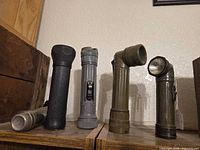 Group of five vintage flashlights on shelf