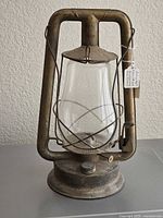 Full view of metal kerosene lantern showing frame, globe, bail and base