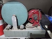 Front view of Lortone lapidary machine showing green grinding wheel, roller supports and red motor