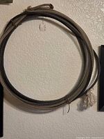 Full view of coiled lasso hanging on wall, showing honda knot and frayed end