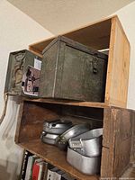 Overview of lot: wooden crates stacked, large metal trunk, small ammunition box, aluminum mess kits