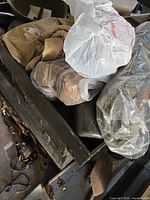 Open olive drab trunk showing helmet, khaki clothing, items in plastic