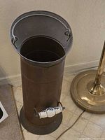 Full view of cylindrical metal umbrella stand with ceramic handle