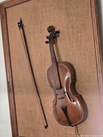 Violin and bow mounted on burlap in wood frame