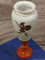 Full view of opaline glass vase on orange pedestal base