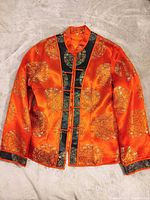Full front view of orange embroidered Chinese jacket