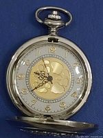 Front view of silver-tone pocket watch open showing skeleton dial and Arabic numerals