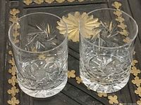 Two clear pinwheel-cut crystal whiskey glasses on dark surface
