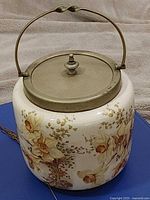 Biscuit jar front view showing floral design and brass handle