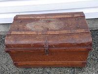 Front and top view of brown metal steamer trunk showing overall form