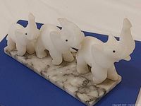 front view of three alabaster elephants on marble base