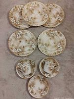 All ten Nippon pieces laid out: five plates, three saucers, two cups