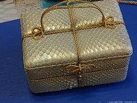 Gold metallic box purse showing rope handle and trim