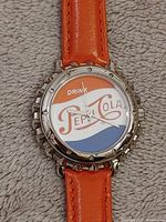 Front view showing Pepsi bottle cap dial and orange strap