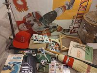 Group shot of all items including poster, cap, books, cards, figurines, broom, racquet, cue and photo