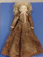 Full view of 12" bisque porcelain doll in brown lace dress
