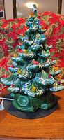 Full view of lit ceramic Christmas tree on base with multicolour peg lights