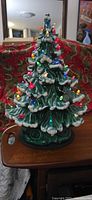 Front view of illuminated ceramic Christmas tree with multicolour bulbs