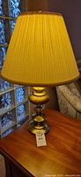 Table lamp on wooden side table lit with pleated shade