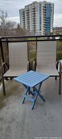 Two sling chairs and blue folding side table on balcony