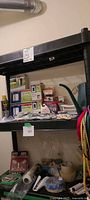 Shelf with assortment of boxed outlets, bulbs, wallplates, hardware, watering can, straps