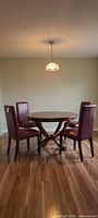 Four dark red faux leather dining chairs around table