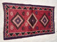 Full view of rectangular red Shiraz rug with three diamond medallions and geometric border