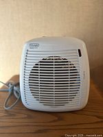 Front view of DeLonghi heater showing grille and cord