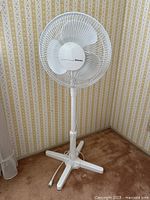 Front view of white Holmes pedestal fan showing full stand and cord