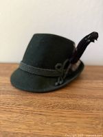 Left-front view showing hat shape, cord band and feather