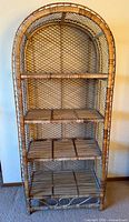 Full front view of arched rattan bamboo bookshelf showing four shelves and lattice back