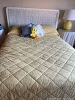 Front view of bed showing headboard, mattress, bedding, pillows and Tweety plush