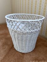 Full view of white wicker wastebasket showing weave and shape