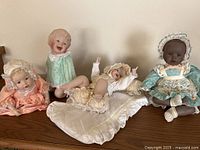 Group shot of four porcelain baby dolls on wooden surface