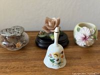 Group shot showing bell, glass trinket box, rose figurine and hibiscus pot