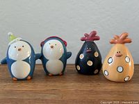 All four ceramic penguin pieces lined up on wood surface