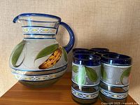Pitcher and five tumblers showing painted design