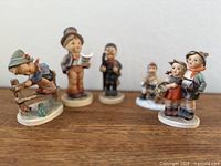 All five Hummel figurines grouped on wooden surface