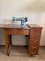 Front view showing cabinet, extension leaf, drawers, machine well