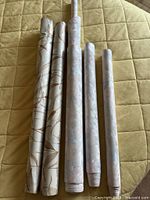 Six wallpaper rolls on quilted surface showing two different patterns