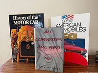 Three hardcover automotive books standing on table