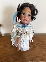 Full view of the 15" porcelain doll on wooden surface