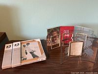 Two boxed Malden frames and three curved glass rose-etched frames on table